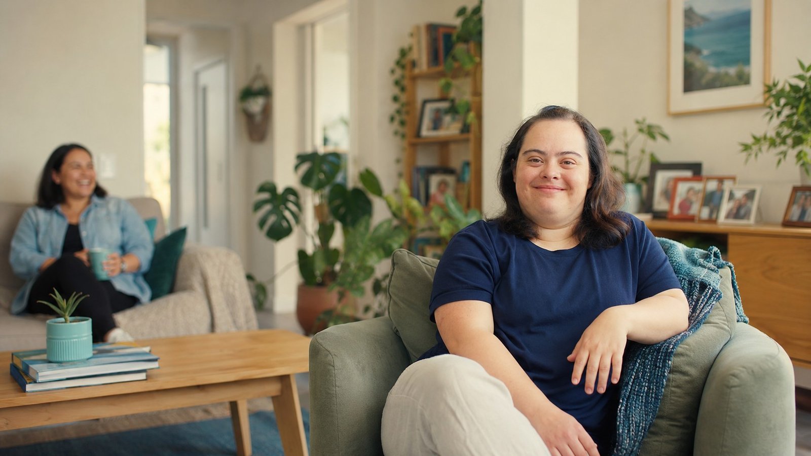 A person relaxed and independent in the living room of their own home, with a support worker nearby