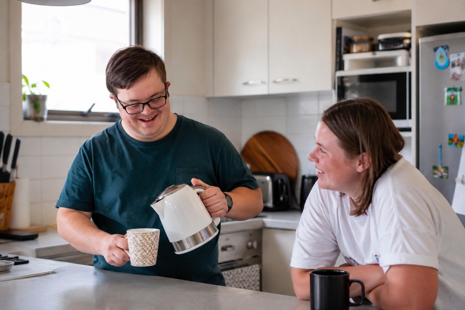 A person with disability comfortable and independent in their own home, making a cup of tea in a bright kitchen