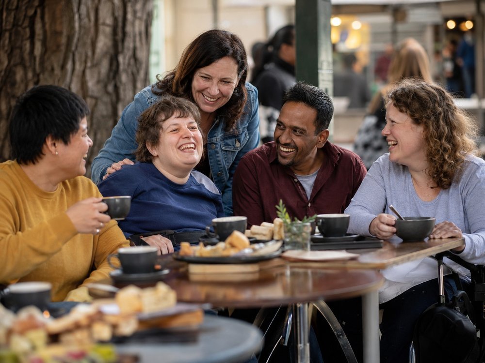 Friends and support workers chatting warmly together over coffee